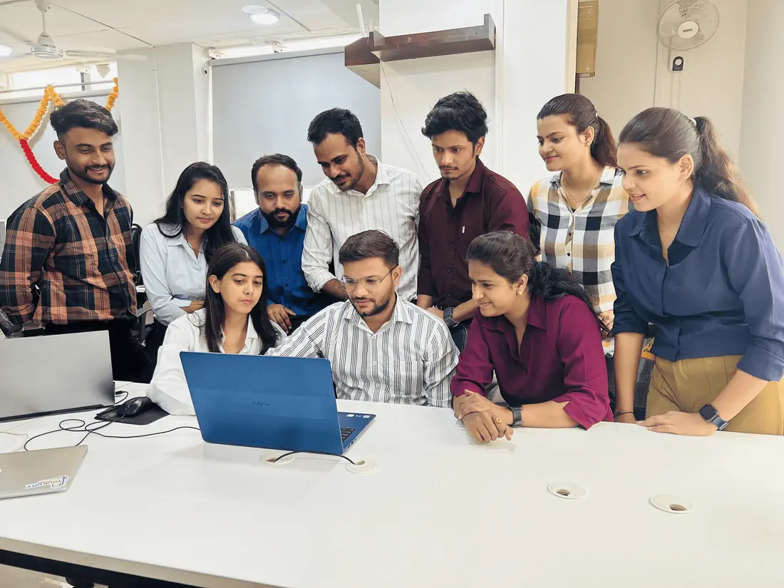 Ten members of the AppWizards team gathered around a laptop at the Indore office