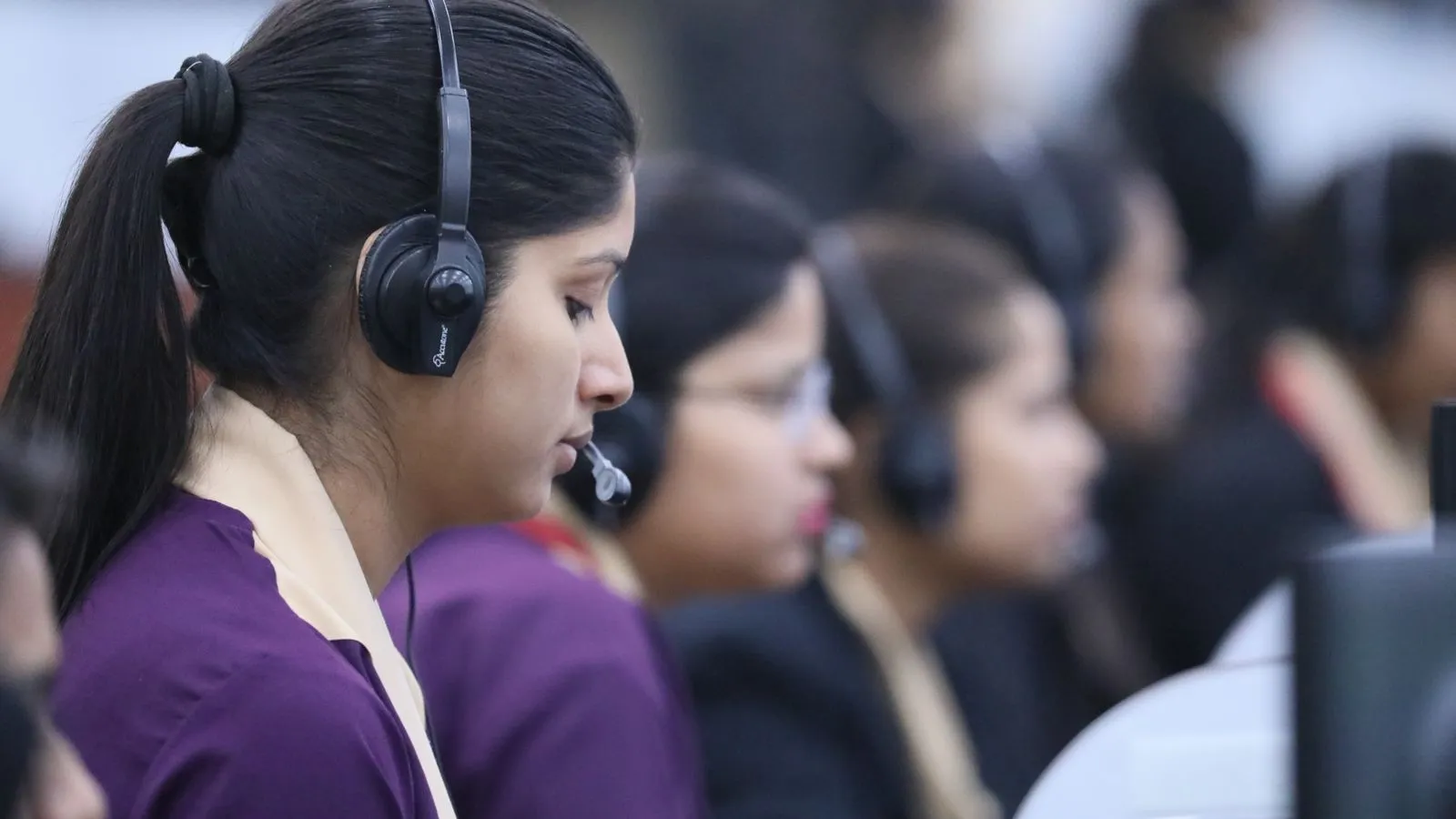 A row of call centre agents in headsets at their desks on an Indian call centre floor