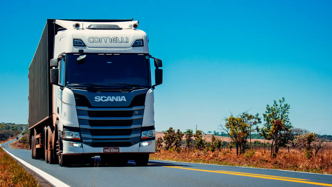 A white long-haul truck parked beside a road under a clear sky.