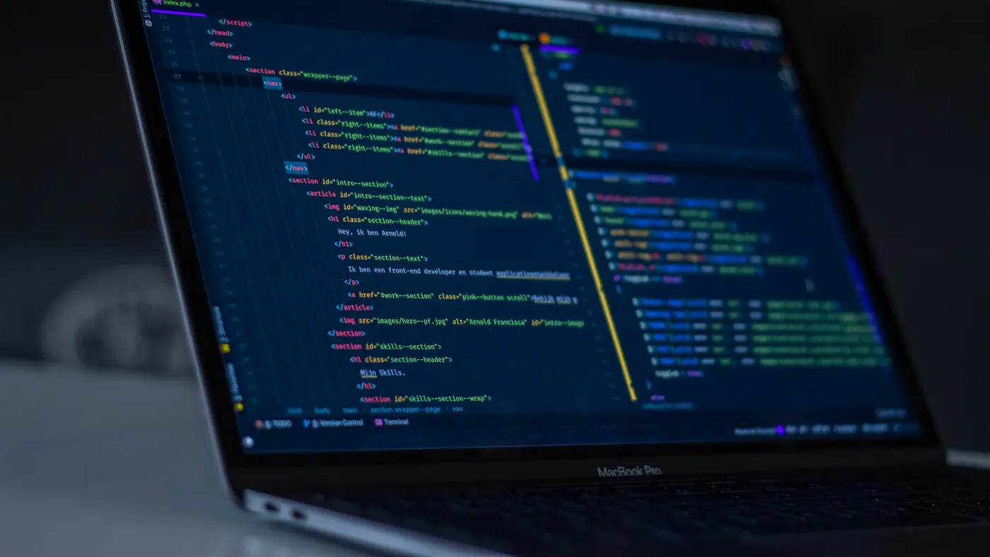 A dark code editor open on a laptop in a dim room.