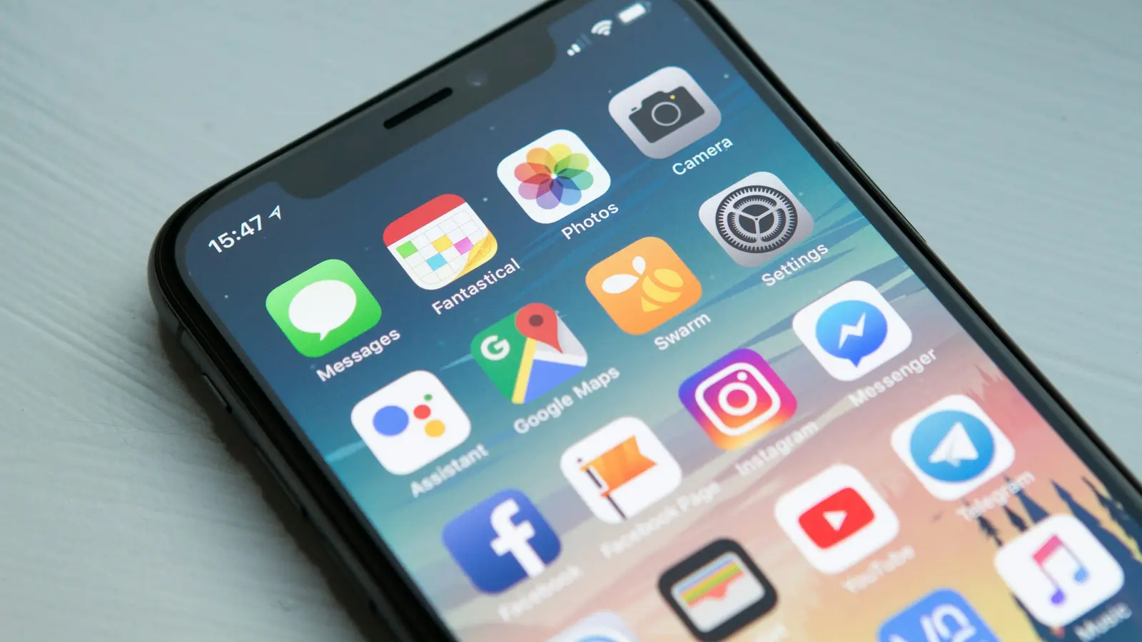 A smartphone home screen filled with app icons, lying on a desk.