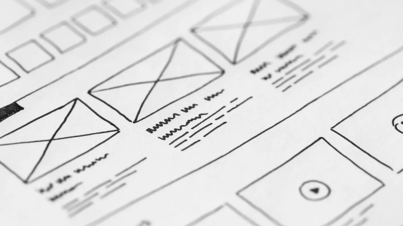 Hand-drawn website wireframes on paper, with boxes and crossed rectangles marking where images will go.
