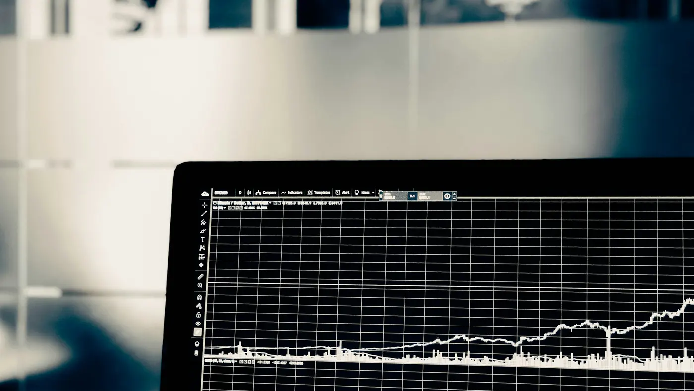 A rising line chart on a dark gridded screen, with volume bars along the bottom.