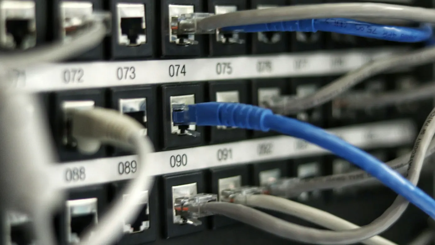 A numbered network patch panel, with blue and grey cables plugged into labelled ports.
