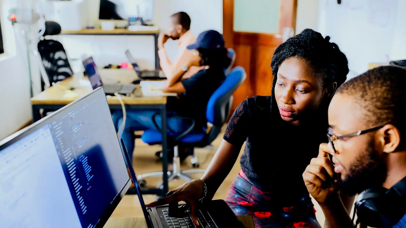 Two people reviewing work together on a computer screen in an office.