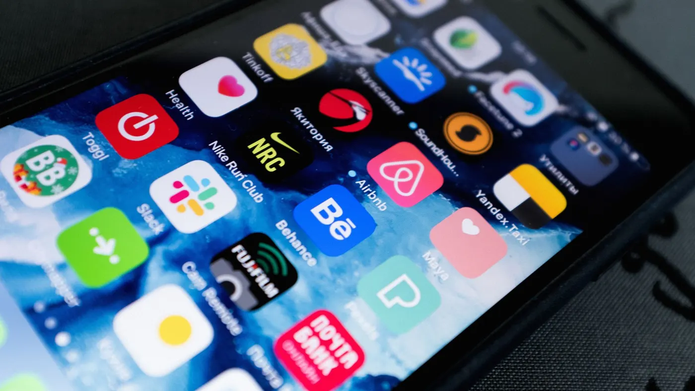 A phone lying on a dark surface with its screen full of app icons.
