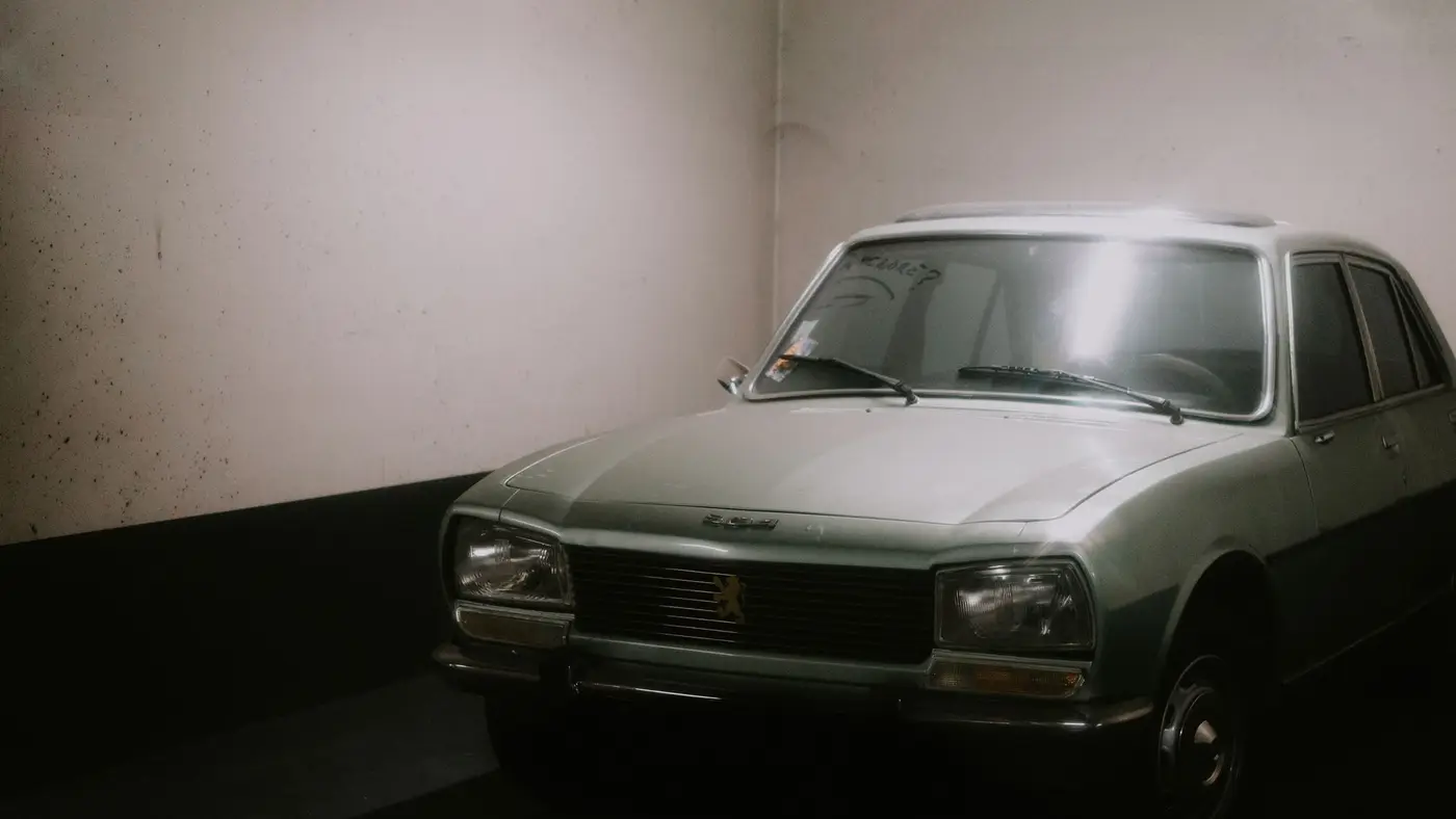 An old car parked in a dim, bare garage.