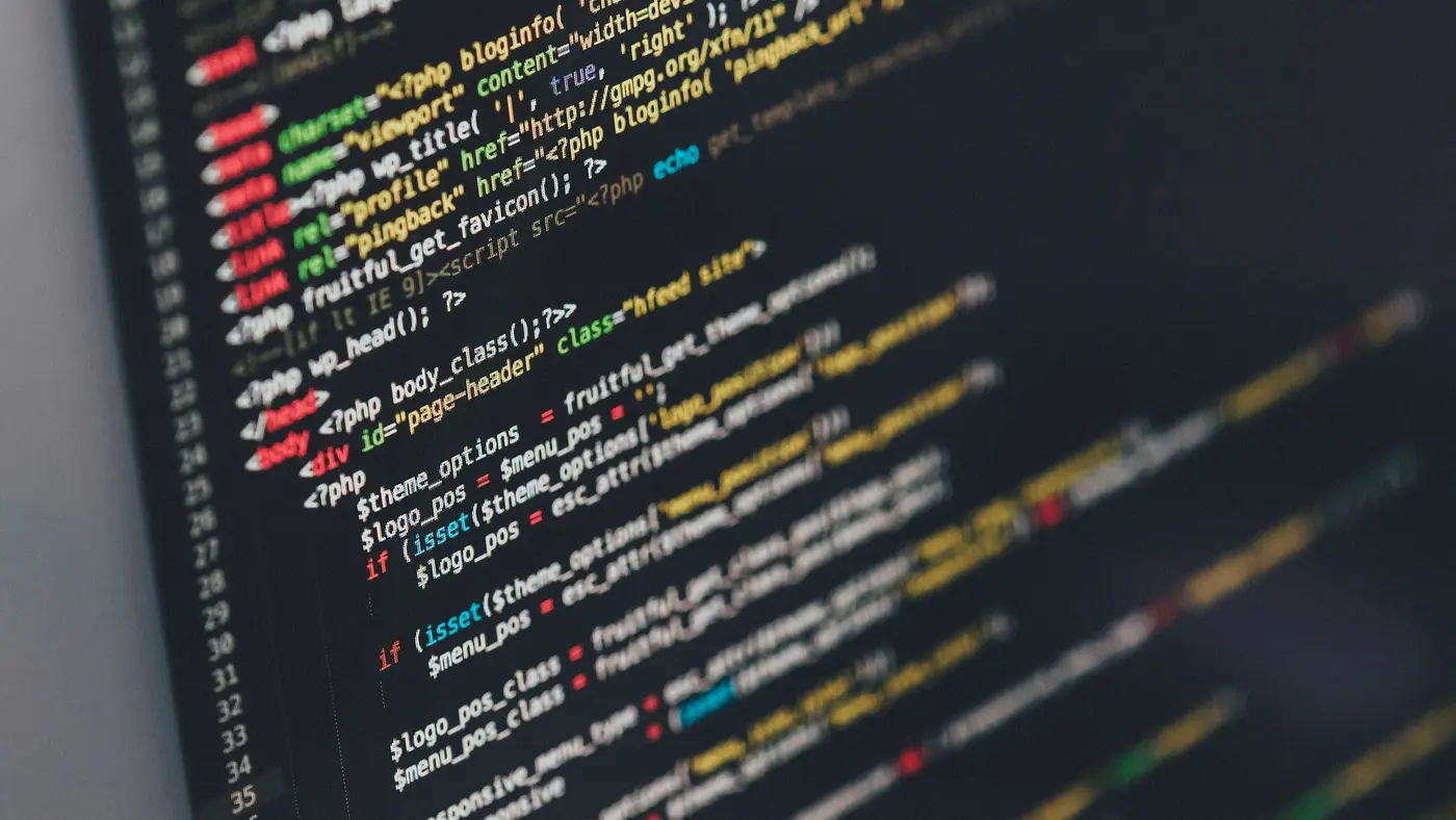 A laptop screen showing colourful code in a dark editor.