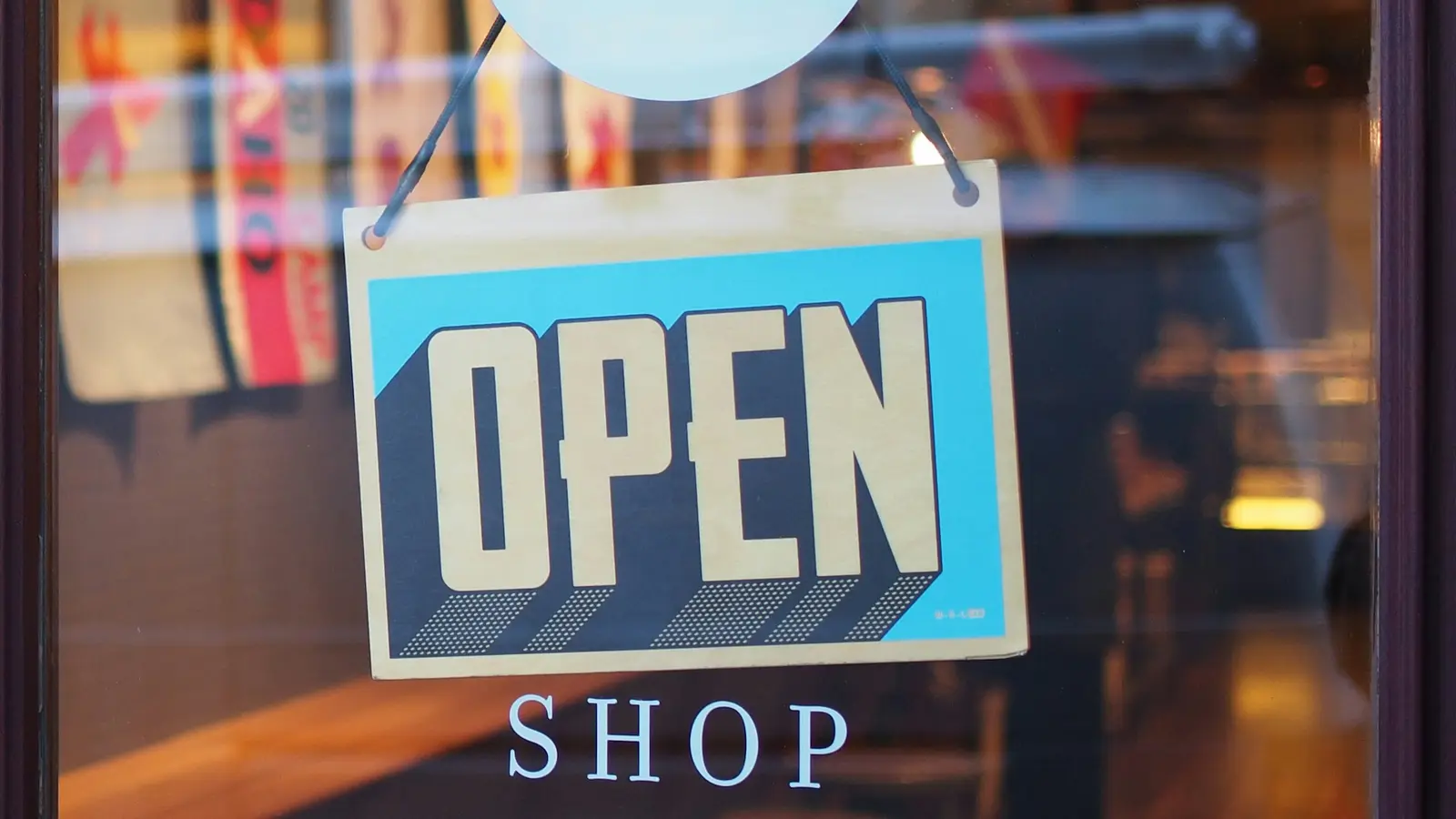 An open sign hanging in the window of a shop, seen from outside.