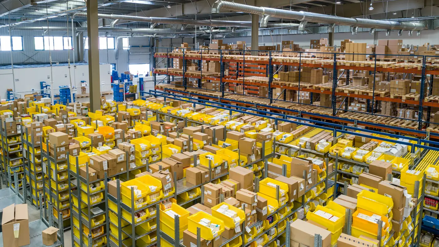 A large warehouse interior with tall racking and yellow shelves stacked with boxes.