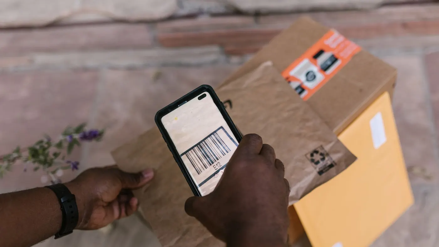 A person scanning the barcode on a cardboard parcel with a smartphone.